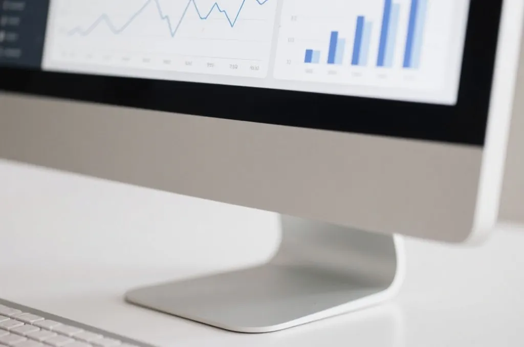 A clean desk with a computer displaying line charts and colorful data visualizations on a dashboard